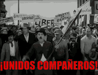 a group of people marching down a street with a banner that says unidos compañeros