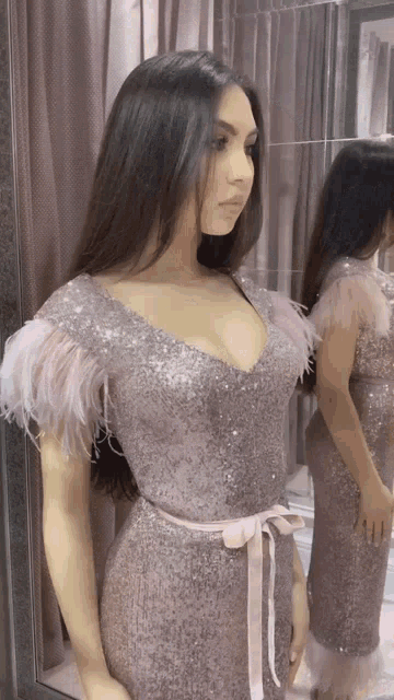 a woman in a pink sequined dress with feathers on the sleeves