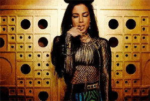 a woman is standing in front of a gold wall with holes in it