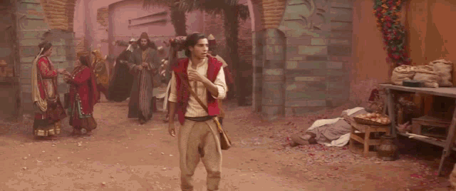 a man in a red vest is walking down a street