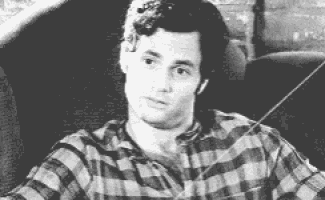 a man in a plaid shirt is sitting in a chair and looking at something .