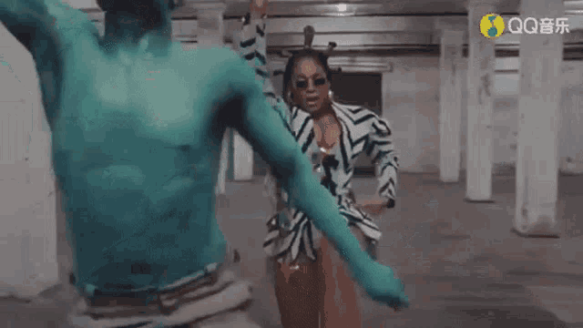a woman in a zebra print dress is dancing next to a man in a blue painted body .