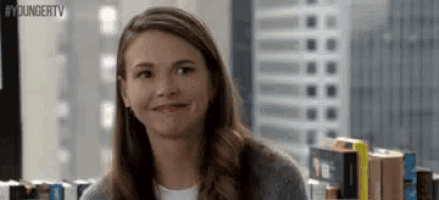 a woman is smiling in front of a bookshelf .