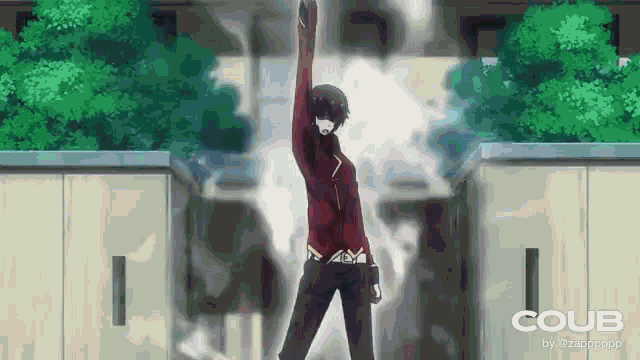 a man in a red jacket is standing in front of a building with his hand in the air .
