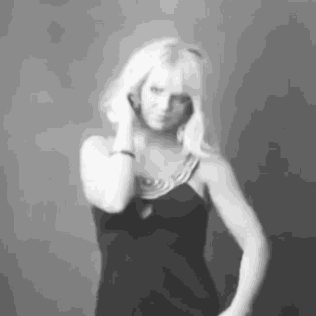 a woman in a black dress is standing in front of a wall in a black and white photo .