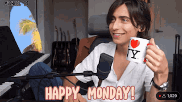a man sitting in front of a microphone holding a mug that says happy monday