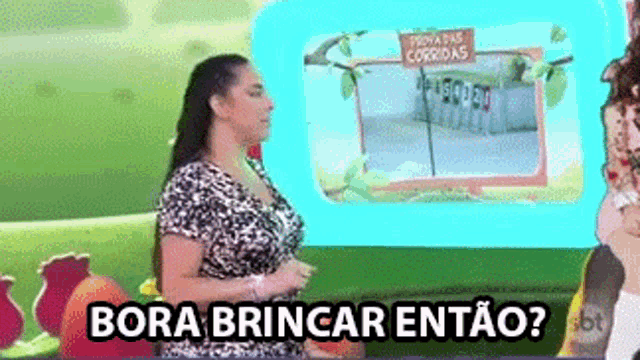 a woman standing in front of a screen that says bora brincar entao .