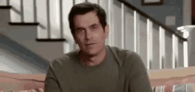 a man is sitting on a couch in front of a staircase in a living room .