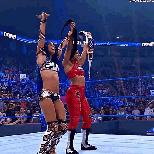 two women in a wrestling ring holding up their belts