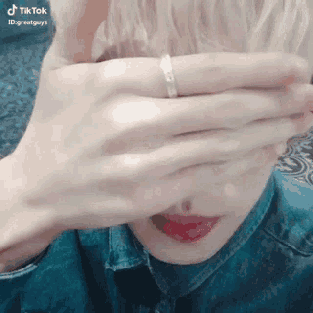 a woman is covering her eyes with her hands .