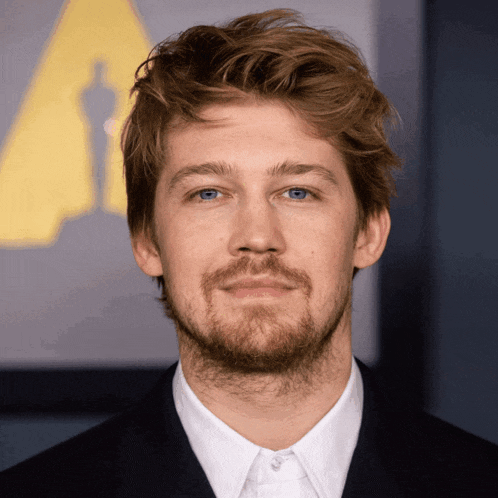 a man with a beard is wearing a white shirt and a black suit