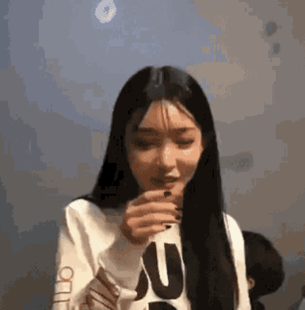 a woman with long black hair is wearing a white sweatshirt with the letter u on it .
