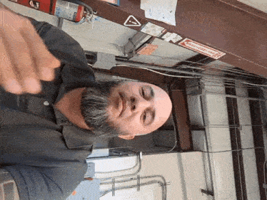 a man with a beard is sitting in front of a fire extinguisher