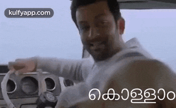 a man is driving a car and smiling .