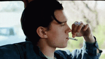 a young man is smoking a cigarette while sitting in a car .