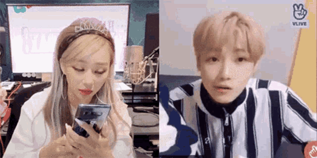a man and a woman are sitting next to each other and looking at their phones .