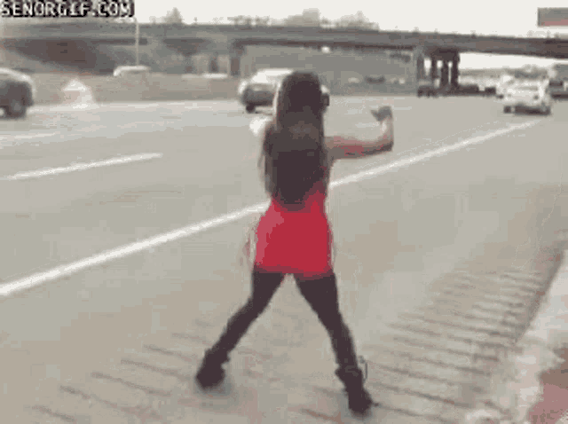a woman in a red dress is dancing on a highway .