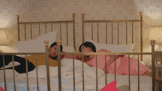a woman in a pink dress is laying on a bed with a man in a red shirt