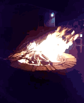a fire is burning in a brick fire pit in front of a house