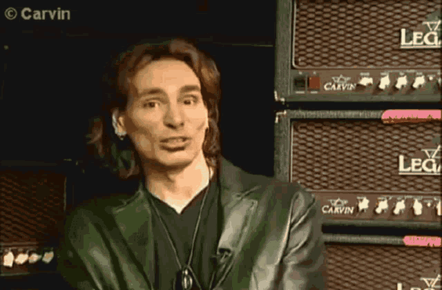 a man is standing in front of a stack of carvin amps