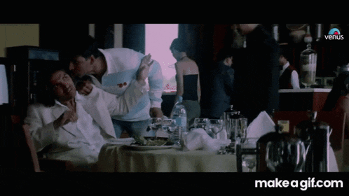 a man in a white suit is standing in front of a table with a bottle of water