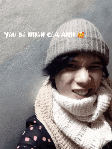 a person wearing a scarf and a beanie with the words yêu be nhan cua anh written on the bottom