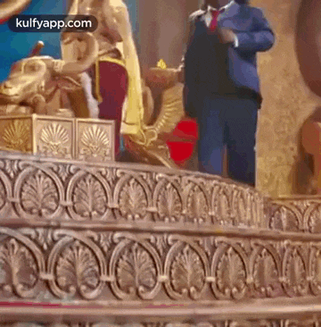 a man in a suit and tie is standing next to a statue of a woman on a stage .