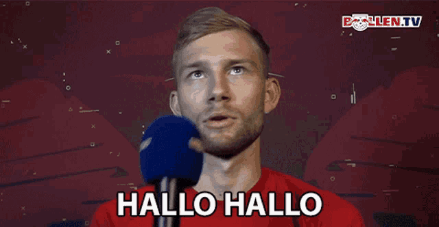 a man in a red shirt is talking into a microphone with the words hallo hallo above him