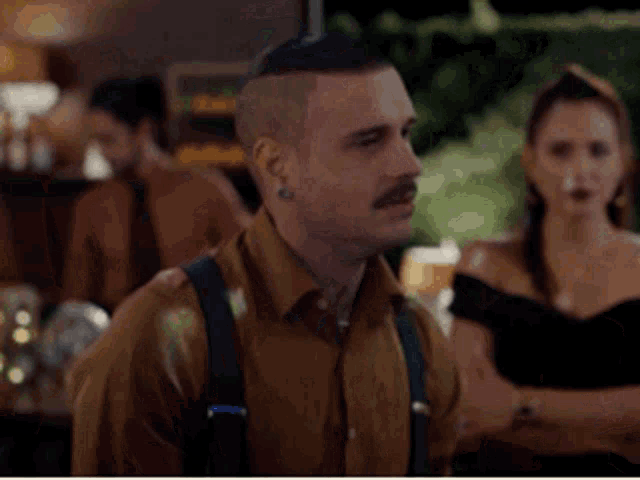 a man with a mustache wearing suspenders and a brown shirt
