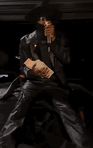 a man in a leather jacket is holding a stack of money in his hands