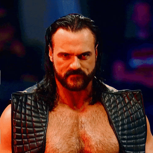 a man with long hair and a beard wearing a black leather vest
