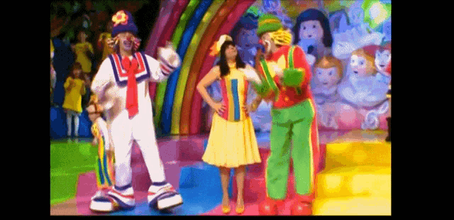 a group of clowns are dancing on a stage in front of a crowd