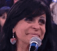 a woman is smiling and holding a microphone in her hand .