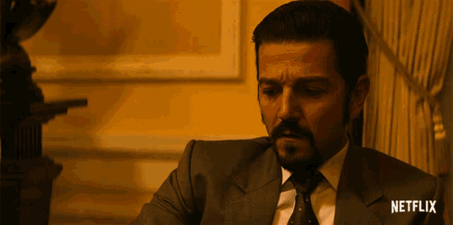 a man in a suit and tie is sitting in front of a netflix sign