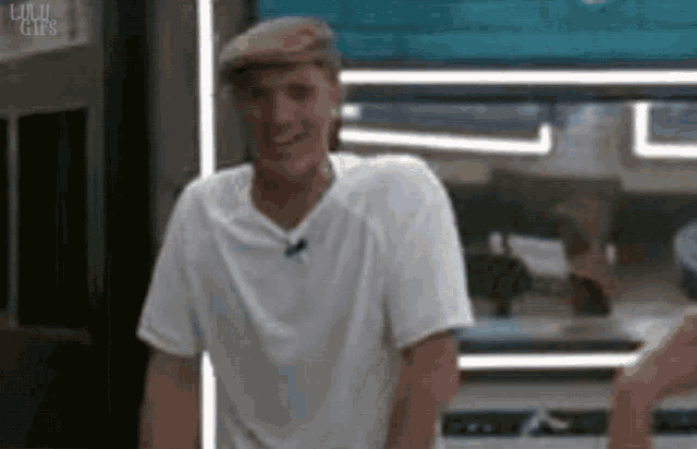 a man wearing a white t-shirt and a hat is standing in a room .