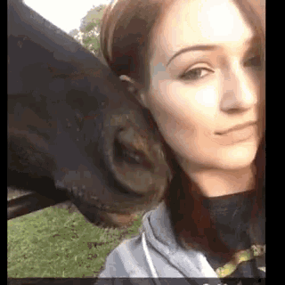 a woman taking a selfie with a horse 's nose on her face
