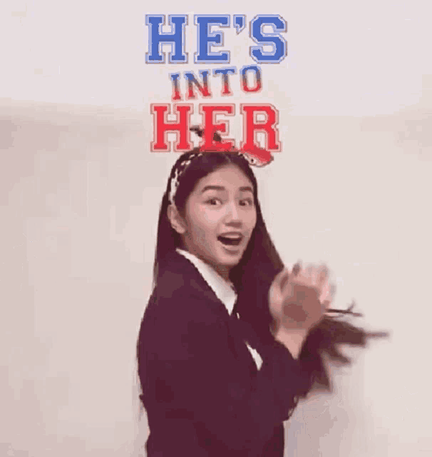 a girl is standing in front of a sign that says he 's into her .