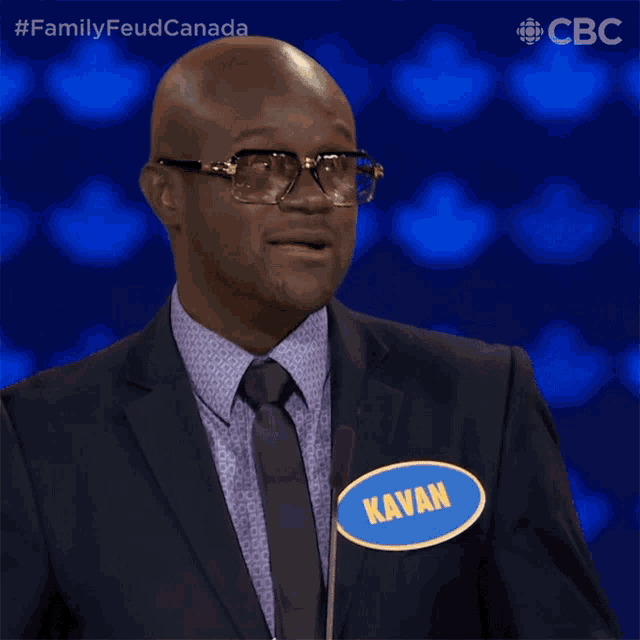 a man wearing glasses and a suit has a name tag that says kavan
