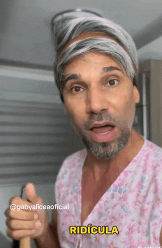 a man with gray hair and a beard is wearing a pink scrub top with the word ridicula on it