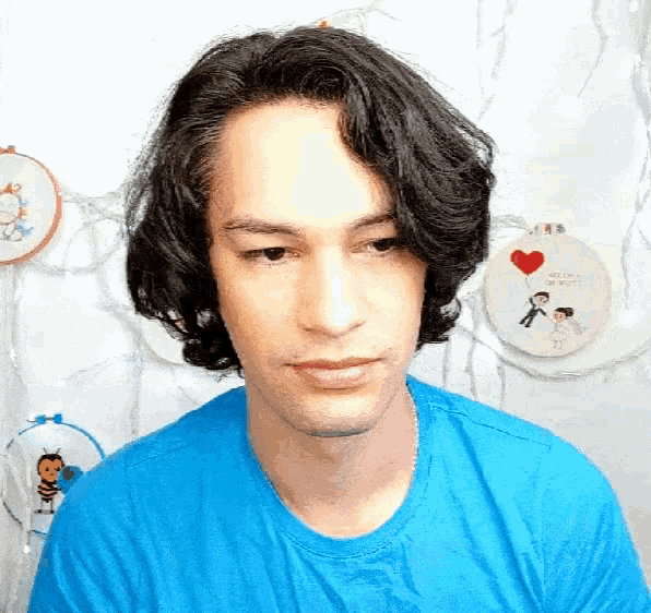 a man in a blue shirt stands in front of an embroidery hoop that says hello kitty