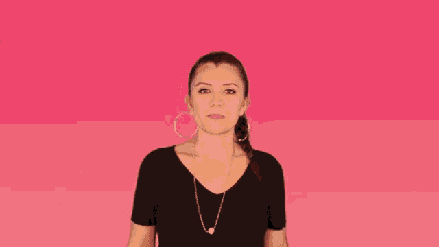 a woman in a black shirt and earrings is making a funny face .