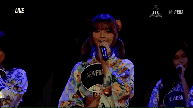 a woman in a kimono singing into a microphone while holding a fan