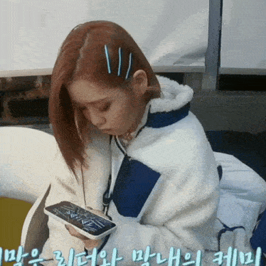 a girl in a white and blue jacket looks at her phone