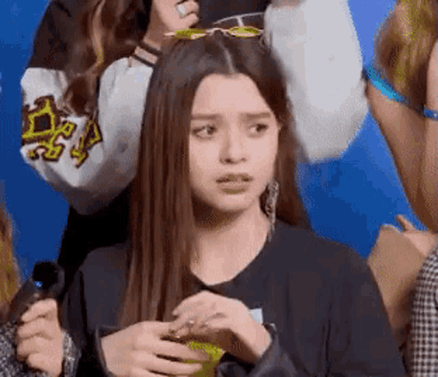 a girl wearing sunglasses and a black shirt is making a funny face while standing in a crowd .