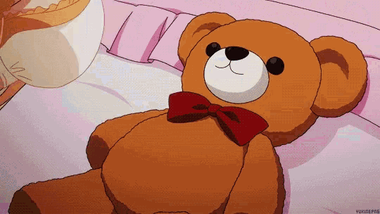 a teddy bear with a red bow is laying on a bed next to a cup of coffee