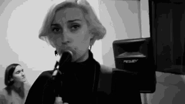 a woman is singing into a microphone in front of a speaker .