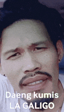 a man with a beard is making a funny face with the words daeng kumis la galigo written above him