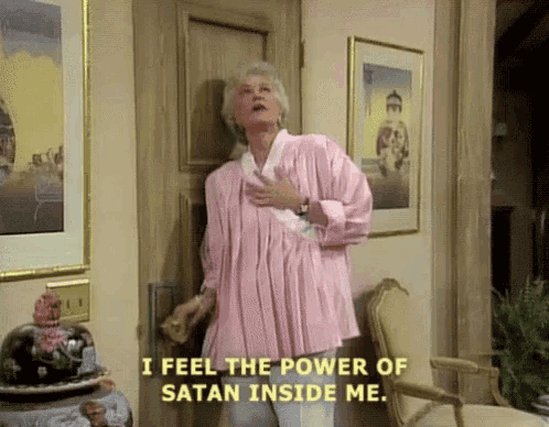 a woman in a pink shirt is standing in front of a door saying i feel the power of satan inside me .