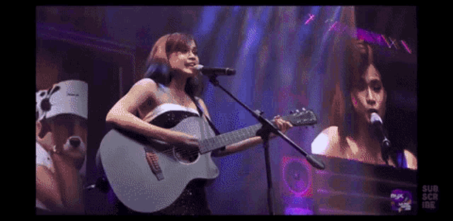 a woman is singing into a microphone while playing a guitar