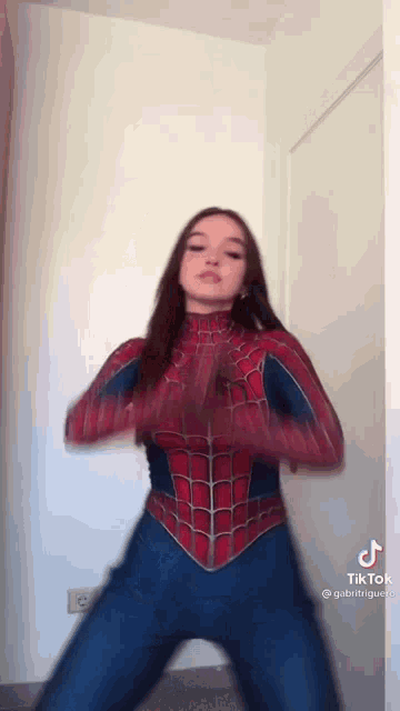 a woman in a spiderman costume is standing in a room .